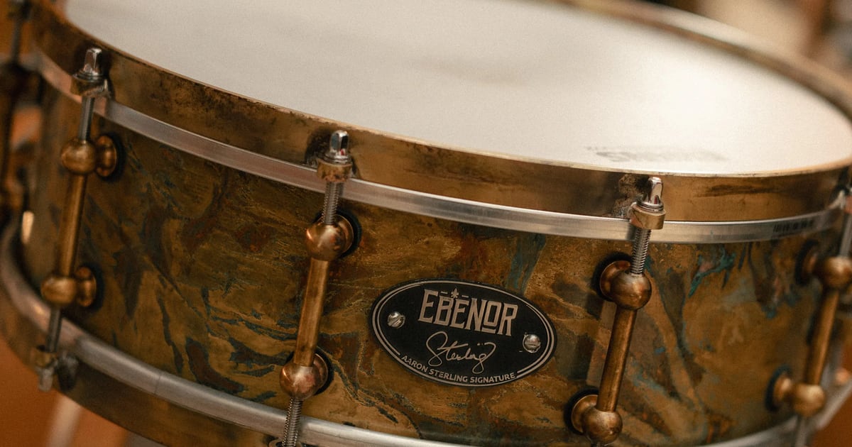 Close-up of the Ebenor Aaron Sterling signature snare, showing the antique patina brass shell, bronze hoops and brass lugs
