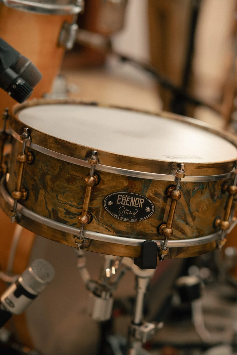 The Ebenor badge and Aaron Sterling signature on the antique patina brass shell, with brass tube lugs and bronze hoops