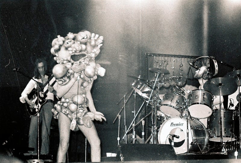 Phil Collins behind his Premier kit with Genesis in 1974, Peter Gabriel in costume at the front of the stage
