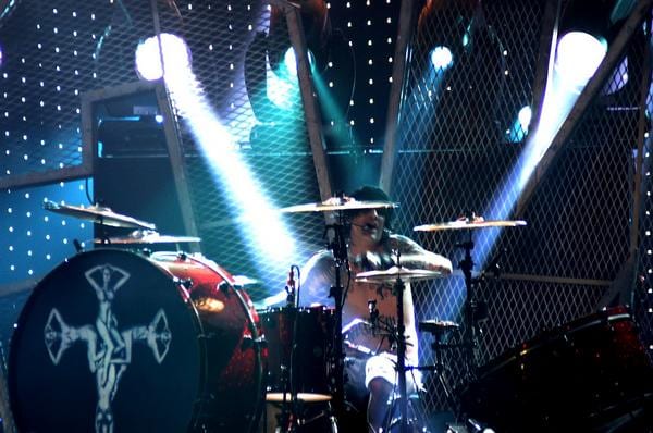 Tommy Lee playing live behind a red sparkle kit