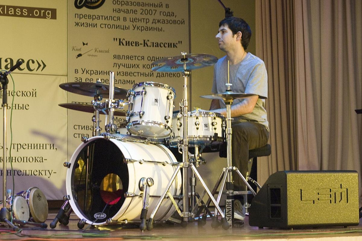 A young Mark Guiliana at a small white Sonor kit on a jazz club stage