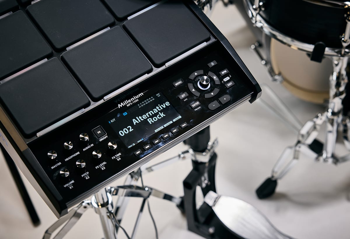 The Nexus module of the Millenium MPS-1500 Hybrid-X, showing its nine rubber pads, colour display reading 002 Alternative Rock, and row of control knobs