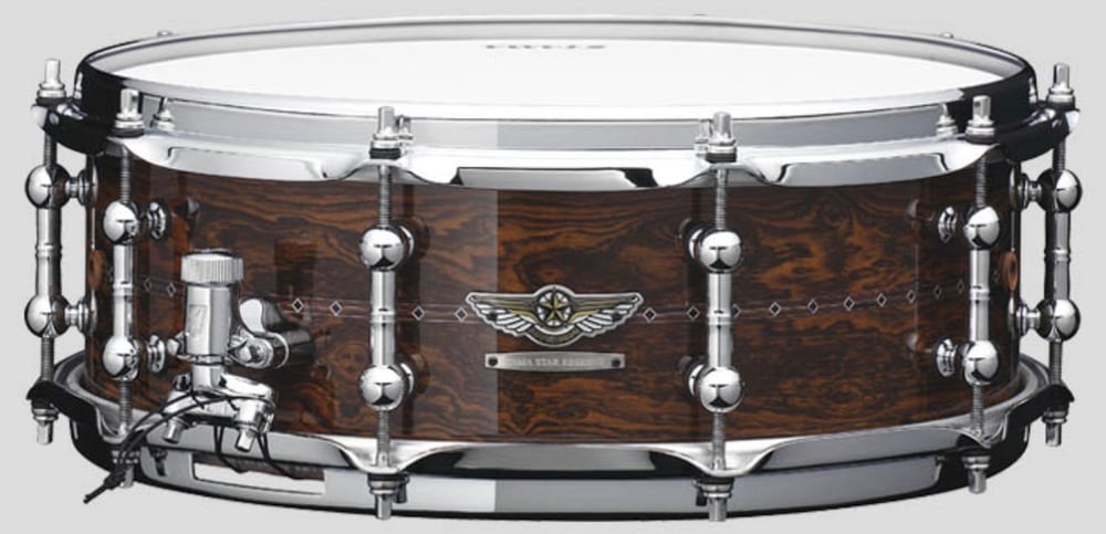 The Tama STAR Reserve Bubinga/Walnut snare in Gloss Claro Walnut, with the STAR wings badge and inlaid diamond detailing around the shell