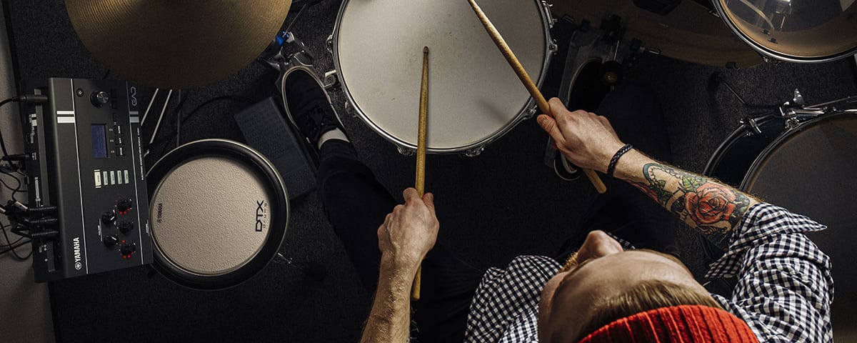 Overhead view of a drummer playing an acoustic kit, with a Yamaha EAD module and a Yamaha pad set up to their left